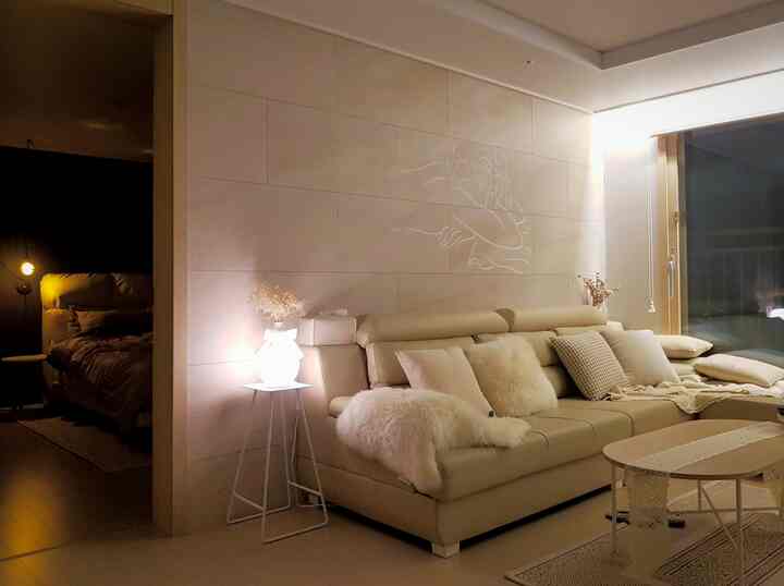Beige-toned living room connected to bedroom featuring genuine leather sofa and mood lighting in natural modern style