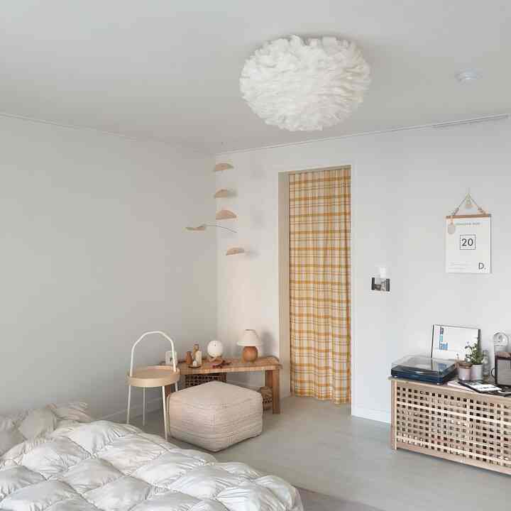 白と木目調が調和した寝室、黄色チェックのドアカーテンとナチュラルな小物が置かれた温かみのある空間