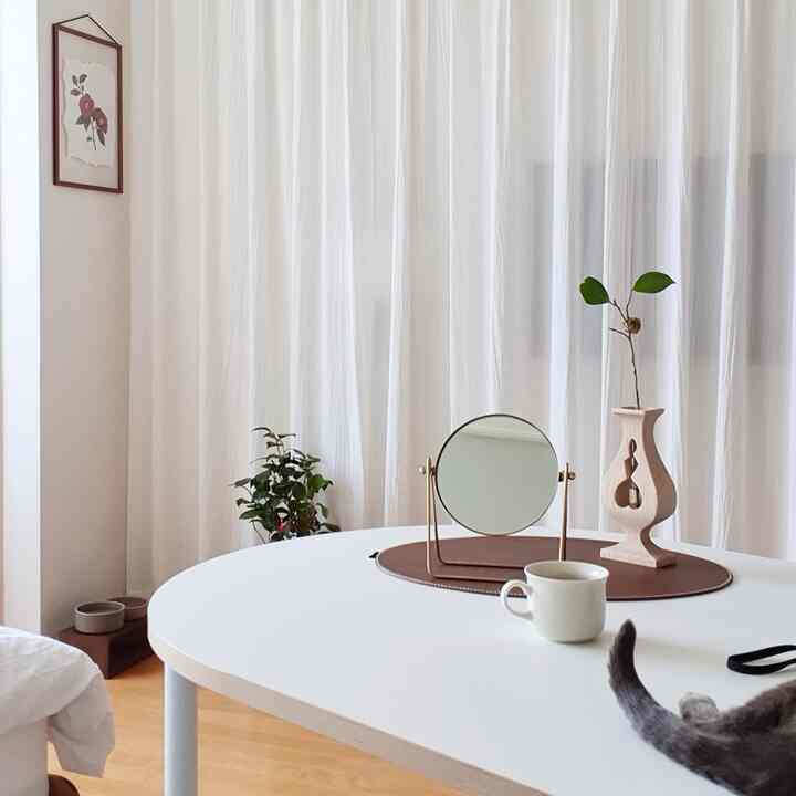 Soft white tone living room featuring sheer curtains, round table with minimal decor creating a natural and tidy atmosphere