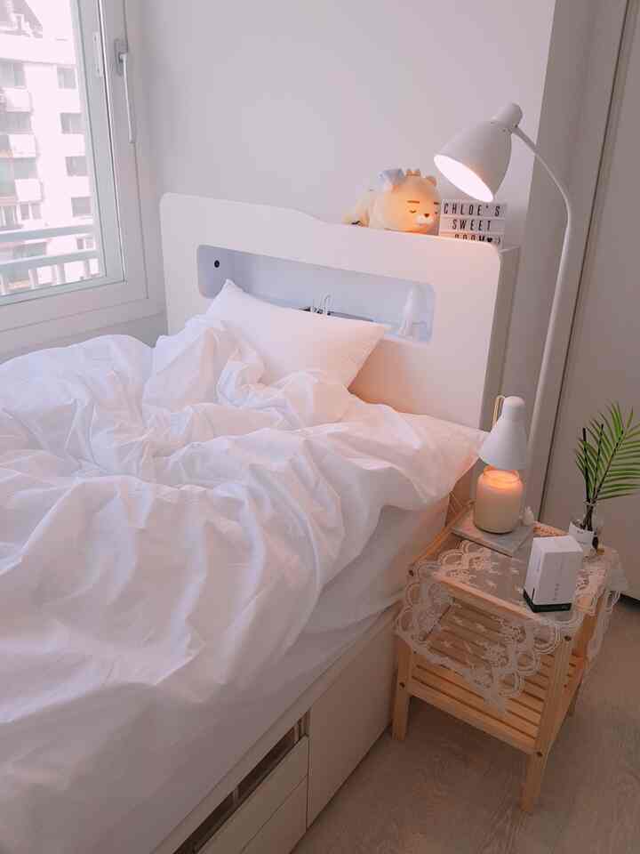 White and wood tone bedroom featuring a neatly made bed and a side table, creating a cozy atmosphere