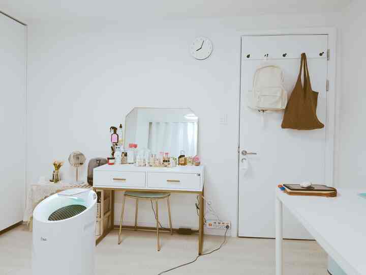 白とナチュラルの色調のコンパクトな部屋、化粧台と鏡が配置された清潔感のあるモダンな空間