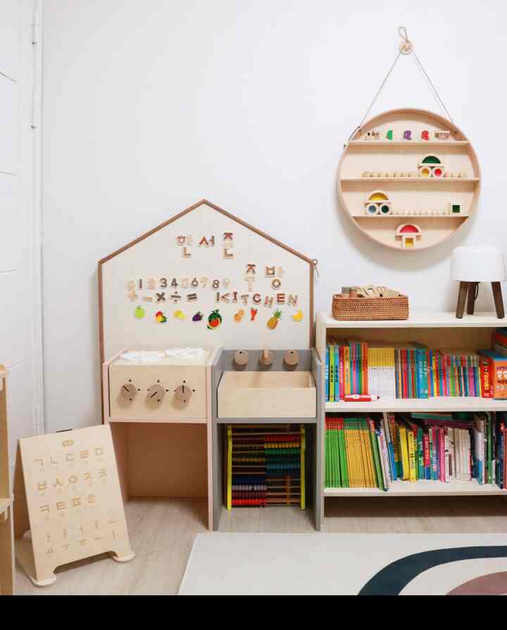 White and wood-tone kids' room featuring wooden toddler furniture and bookshelf with a natural, clean atmosphere