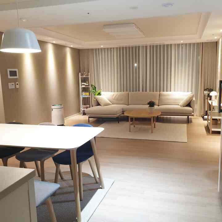 Beige and wood tone living and dining room featuring a comfortable sectional sofa and wooden coffee table in a modern space