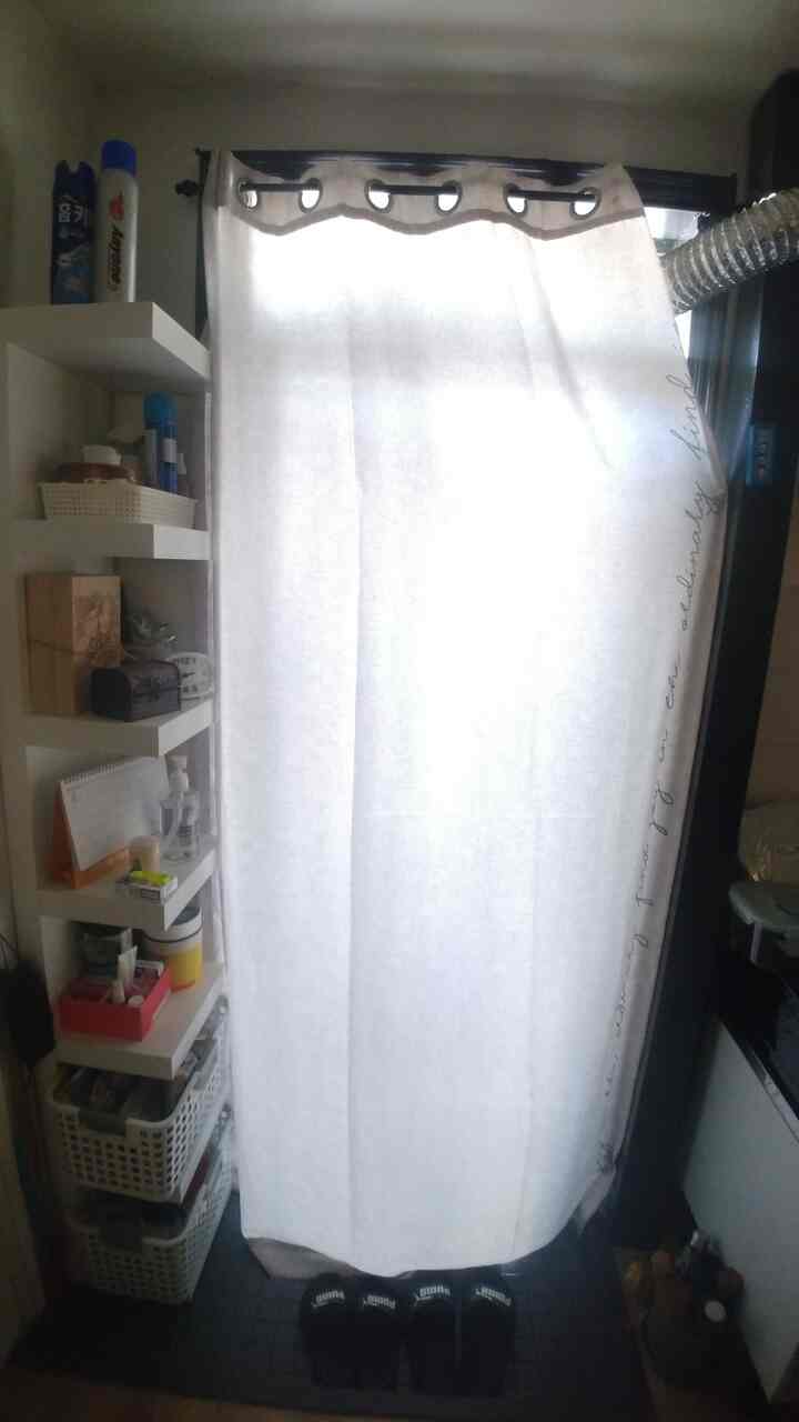 Narrow entrance area with a white curtain and wall-mounted shelf, showcasing a practical and tidy atmosphere