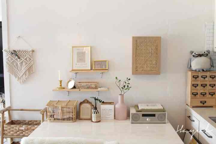 Natural toned living room corner featuring a desk decorated with wood and rattan accessories creating a cozy atmosphere.