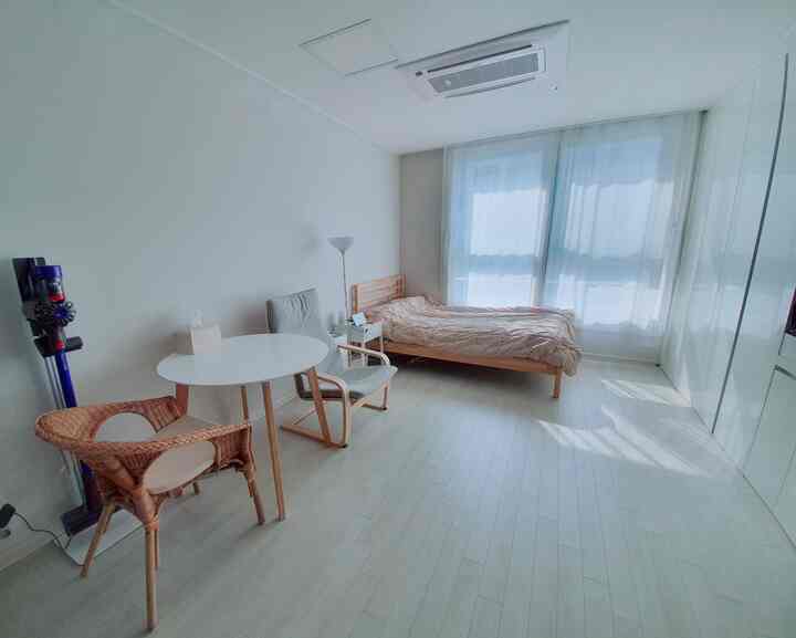 Bright white floor and walls featuring wood tone furniture in a compact 9-pyeong studio bedroom space