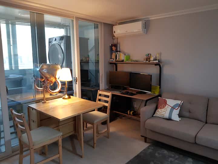 ウッドトーンとベージュが調和したコンパクトなリビング、多目的に使える折りたたみダイニングテーブルとホームオフィスデスクが配された落ち着いた空間