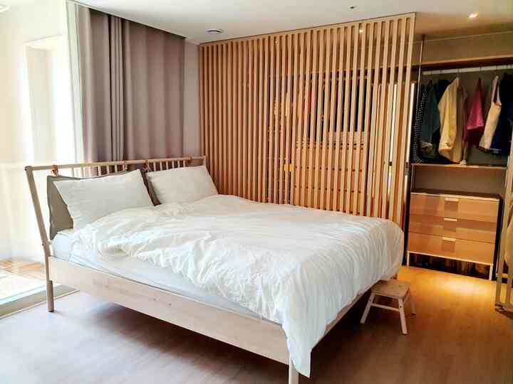 木目調と白が調和したナチュラルでシンプルな寝室、木製家具と清潔感のある掛け布団カバーが配置された落ち着いた空間