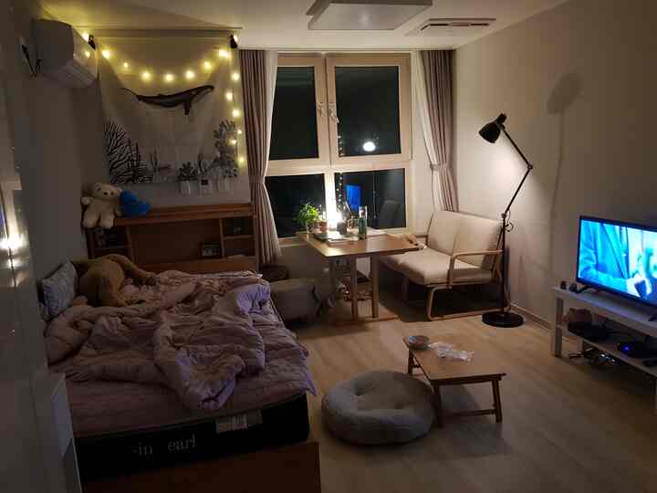 A cozy 7-pyeong studio apartment featuring wood tones and white hues with bed and dining table arranged