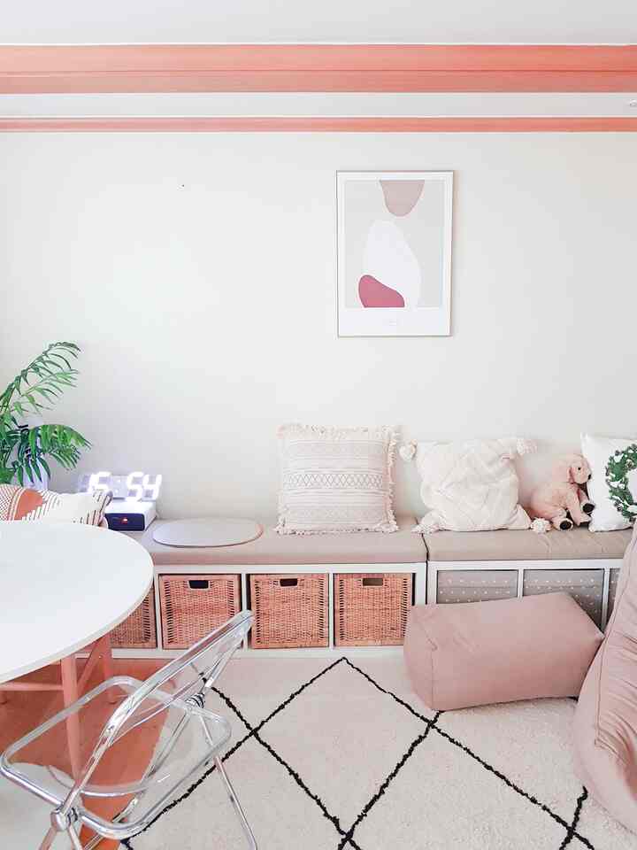 白い壁とピンク色のベンチ、ビーズクッションが配置されたダイニング兼リビングの空間