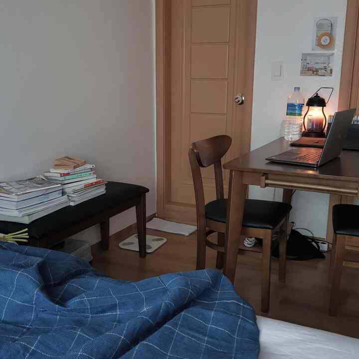 白い壁と木目調家具のあるワンルーム、コンパクトなダイニング兼作業スペースの雰囲気のあるインテリア