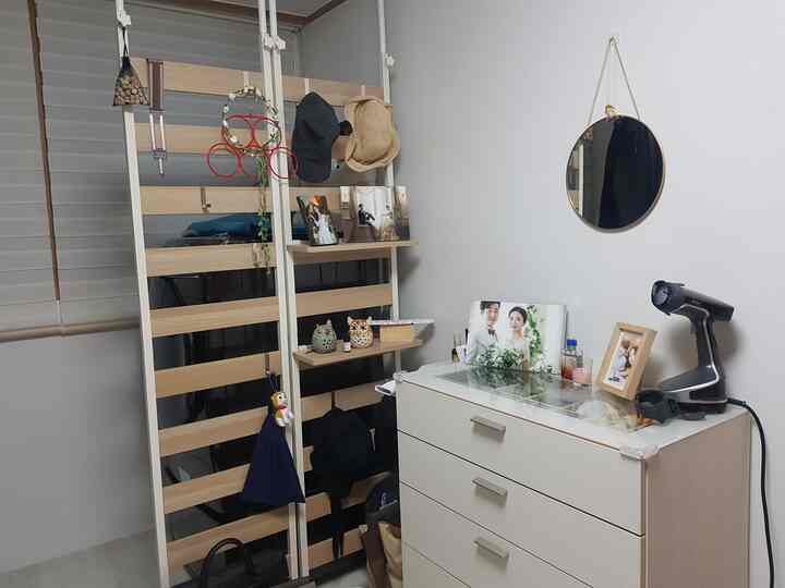 Bright white and gold-accented walk-in closet featuring wooden partition and dresser in a neat space