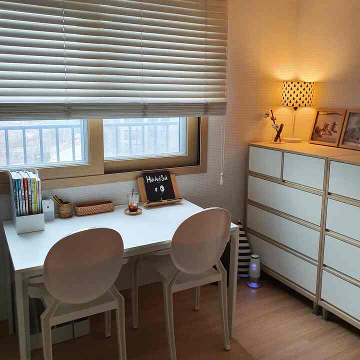 ホワイトと木目調が調和した子供部屋、窓際にデスクとチェストが配置された整った空間