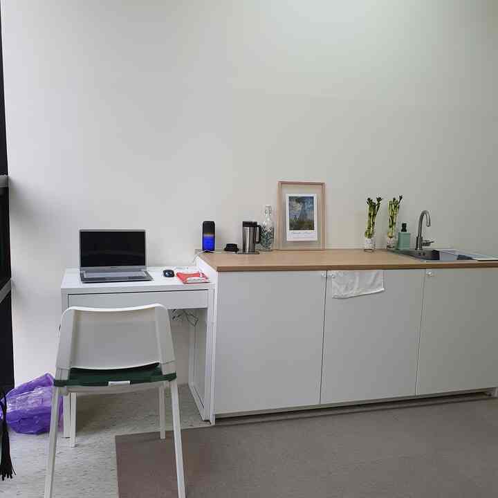 Monotone white workspace corner with wooden countertop and laptop for a simple, modern home office