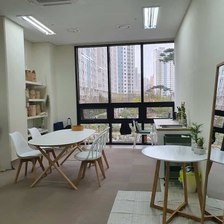 White and wood tone dining room featuring large windows and a compact kitchenette with a clean, natural atmosphere