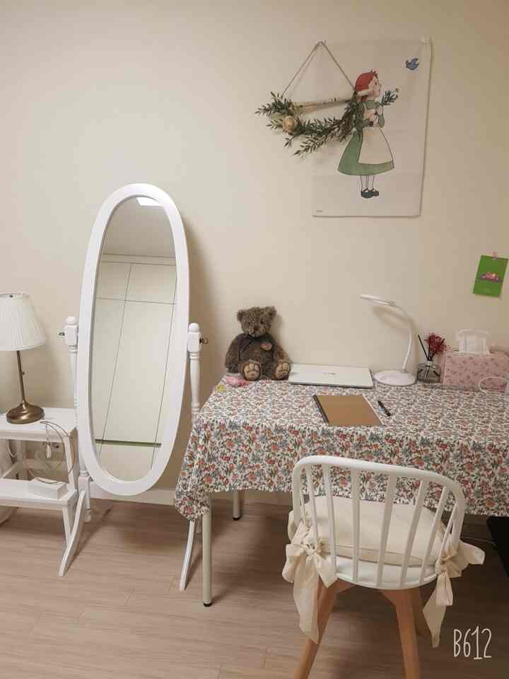 White and wood tone bedroom workspace featuring full-length mirror and wall decor with cozy atmosphere