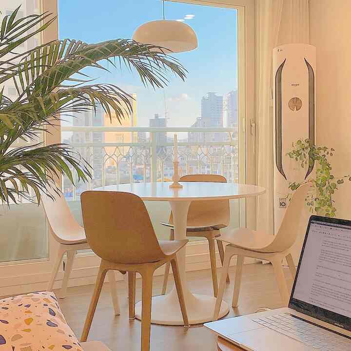 Bright veranda space in white and brown tones featuring a round table and chairs, creating a cozy and airy home cafe living area