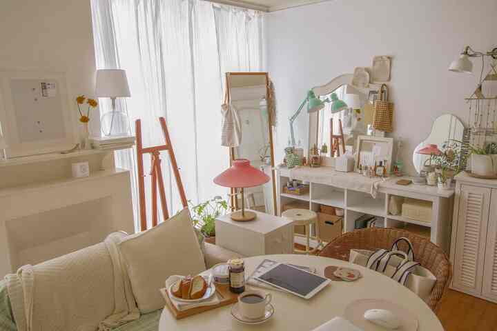 白とナチュラルな木目調が調和した寝室、丸テーブルとソファ、多様な小物が配置された雰囲気のあるインテリア