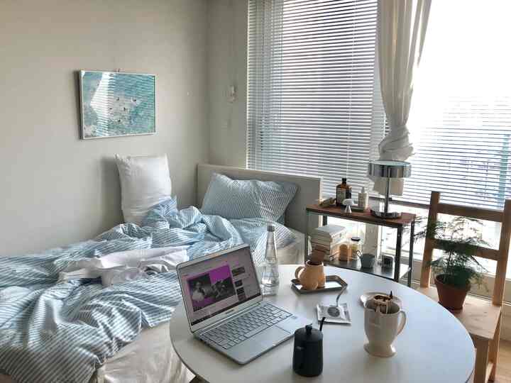 White and blue toned bedroom featuring a small desk, shelving, and bright window for a cozy atmosphere