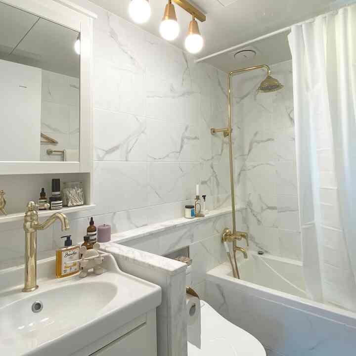 Luxurious bathroom space featuring white marble tiles and gold fixtures creating elegant harmony