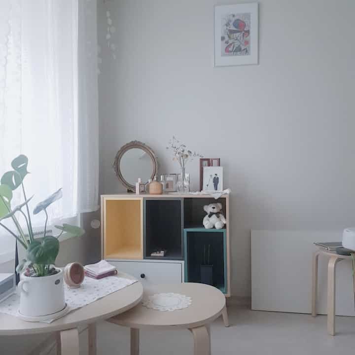 White and light brown toned bedroom featuring plants by the window and small furniture in a natural atmosphere