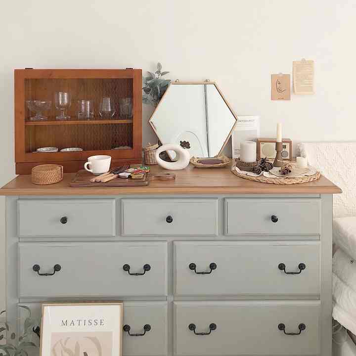 Natural modern dresser with white walls and wood tone top, featuring a hexagonal wall mirror and organized decorative items