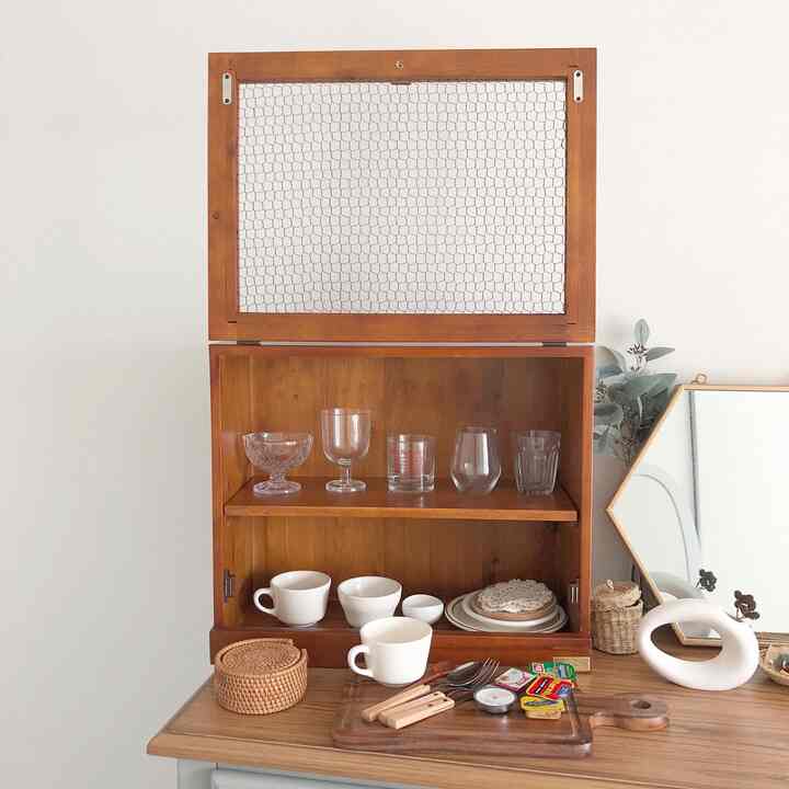 ナチュラルな木目調とホワイトの壁が背景のキッチンスペース、木製ミニ食器棚に透明なグラスと白いカップが整然と配置された雰囲気のあるインテリア