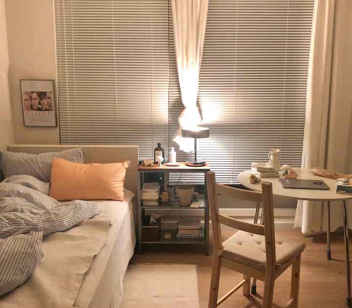 Cozy bedroom with warm natural tones featuring a bed, round table, and simple wooden furniture