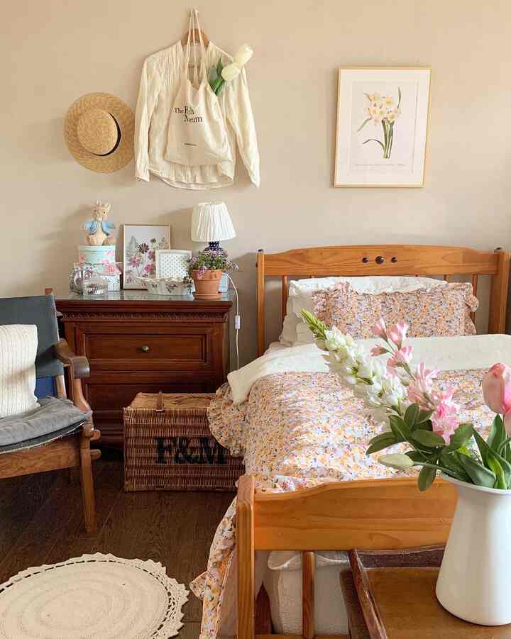 ベージュとブラウンの木目調の寝室、花柄の寝具と小さな鉢植えが置かれた自然な雰囲気のインテリア