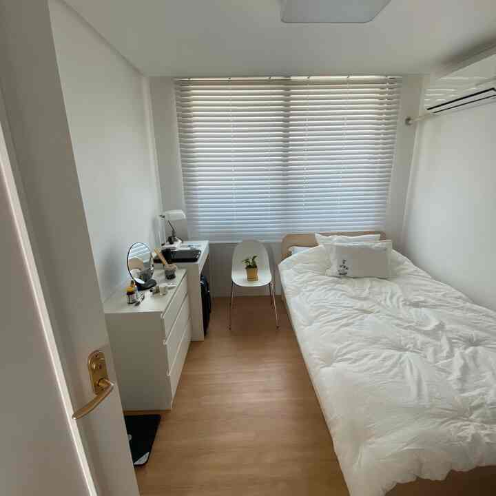 White and wood-tone single bedroom featuring simple furniture layout with a clean, cozy atmosphere