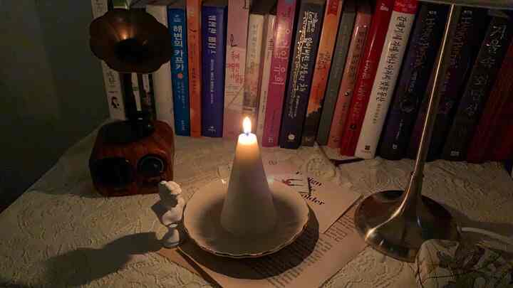 Cozy interior space featuring a white cone candle on a gold-trimmed plate with a retro bookshelf backdrop