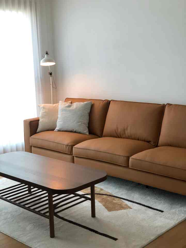White and brown toned living room featuring a brown leather sofa and wooden coffee table with a natural and modern ambiance