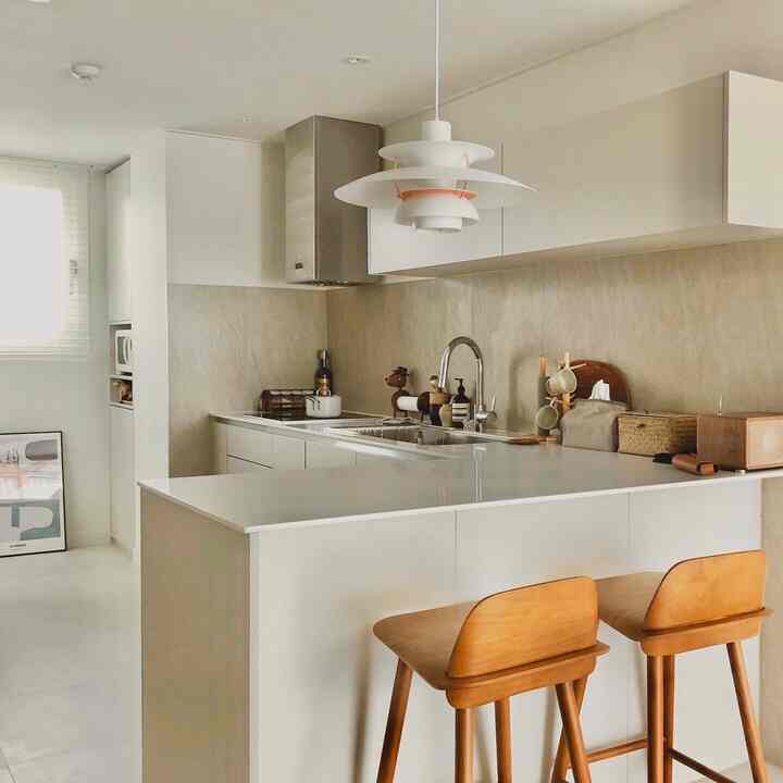 白と木目調のキッチン、キッチンアイランドとバースツールが配置されたシンプルでモダンな雰囲気のインテリア