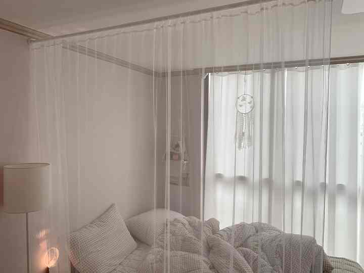 Soft white-tone bedroom featuring checkered bed and floor lamp creating a cozy atmosphere