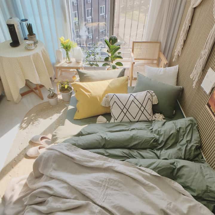 Cozy bedroom with warm natural and wood tones, featuring a home cafe setup and various plants bathed in soft sunlight