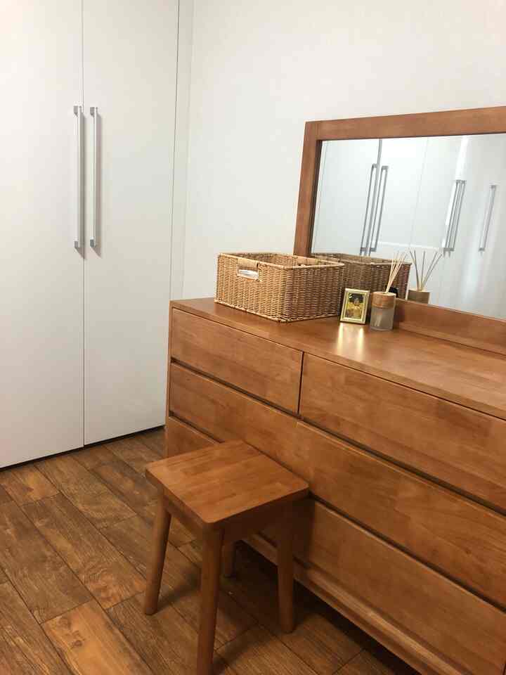 温かみのある木目調とラタンアイテムが配されたシンプルな寝室の化粧台スペース