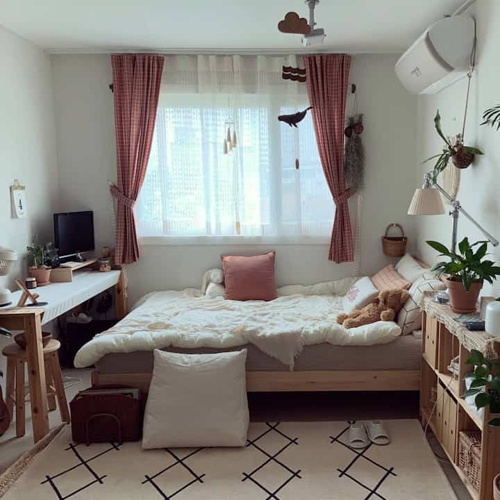 Beige and white toned studio bedroom featuring wooden furniture and green plants in a cozy setting