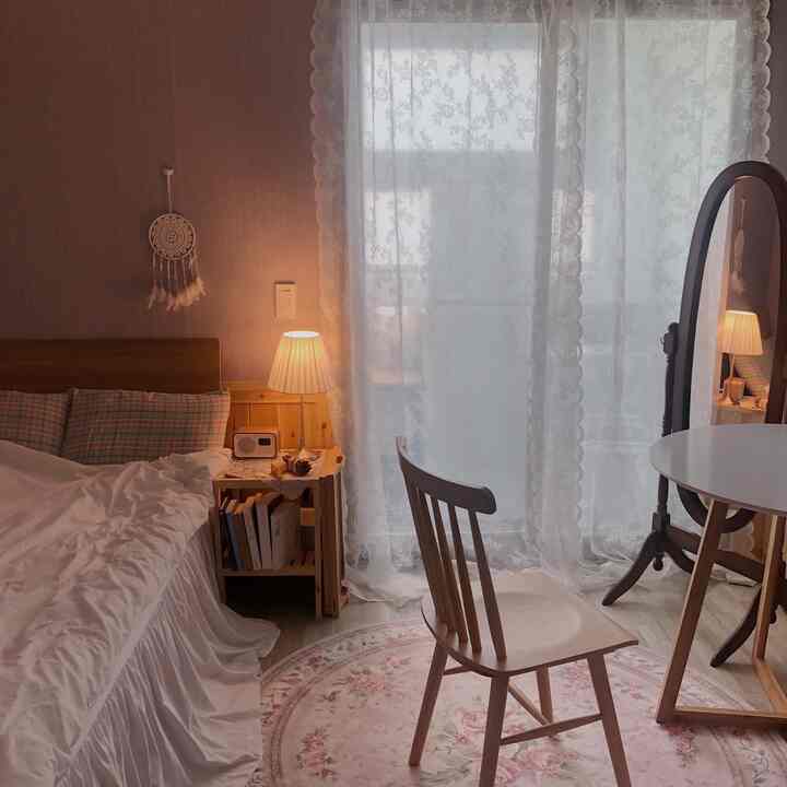 A cozy bedroom in soft natural tones featuring wooden furniture and lace curtains with warm lighting