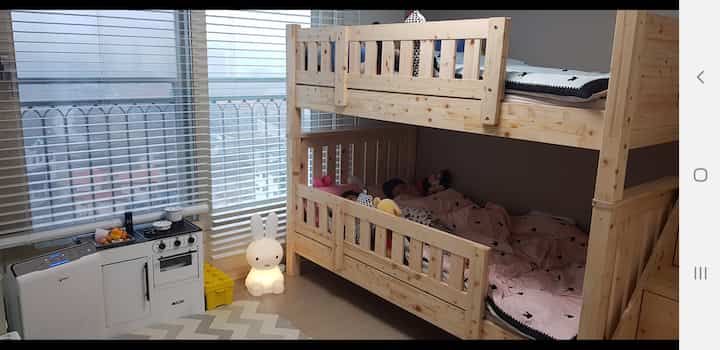 Natural wood-tone kids' room featuring a bunk bed and pastel toys, with two boys sleeping cozily