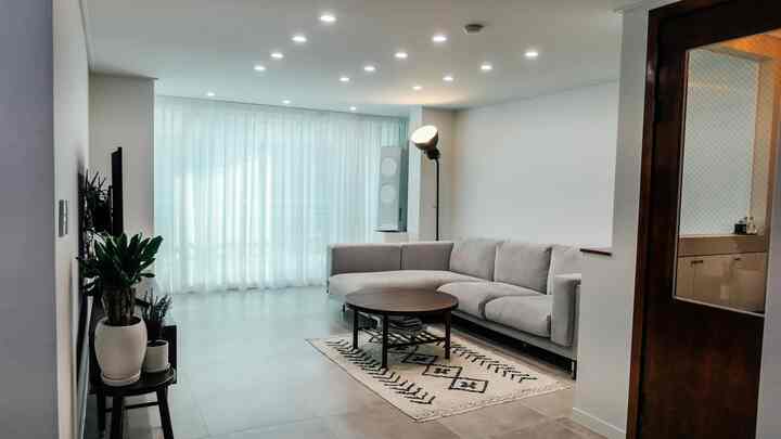 A white and beige toned living room featuring a gray sofa and wooden coffee table in a semi-vintage style