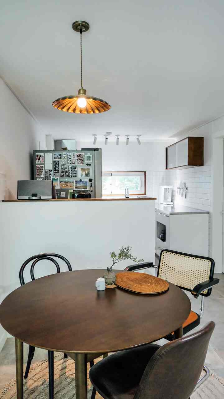 白と木目調が調和するダイニングとキッチンの空間、丸いダイニングテーブルと多様な椅子が配置された雰囲気のあるインテリア