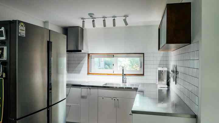 White and stainless steel kitchen featuring IKEA base cabinets and stainless steel countertop with natural wood tones, neat and modern setup