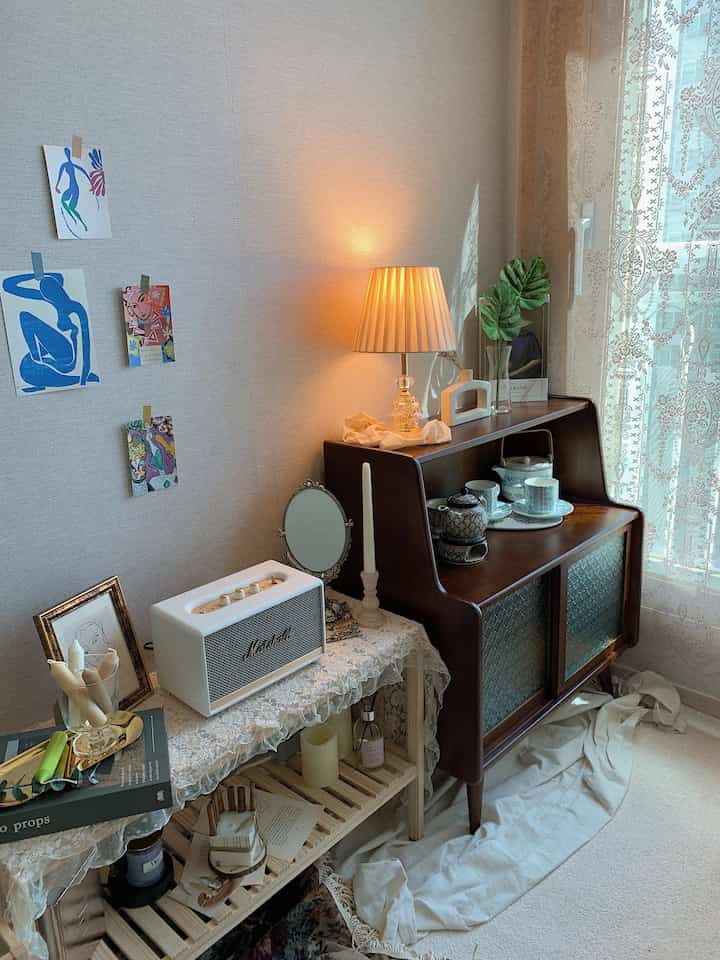 Cozy home cafe space with natural tones featuring wooden cabinet, lace curtain, and Bluetooth speaker creating a warm atmosphere