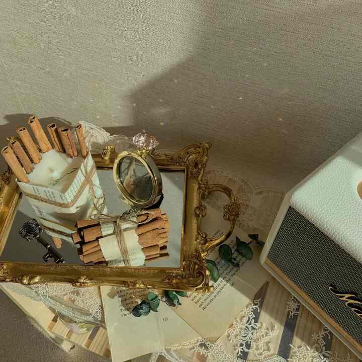 Beige-toned home cafe space featuring a gold tray with cinnamon candle and white Bluetooth speaker on a cozy table