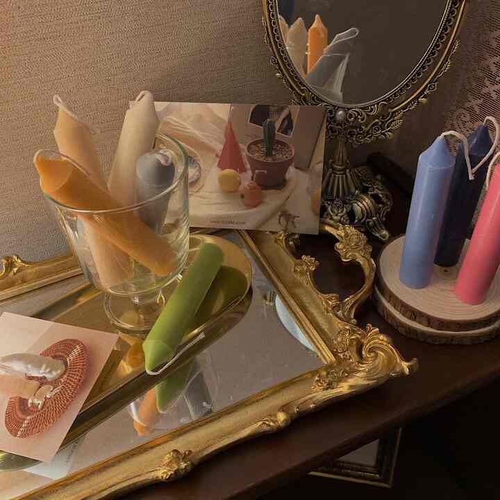 Warm gold antique mirror and tray with colorful candles arranged on wood tone surface in a cozy emotional interior setting