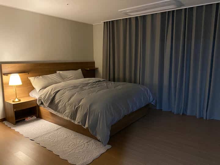 Cozy newlywed bedroom with gray bedding, brown wood-tone bed frame and nightstand
