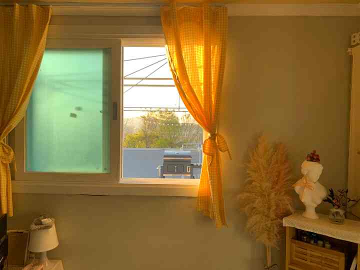 Cozy small room in warm yellow tones featuring yellow gingham curtains and natural decor elements