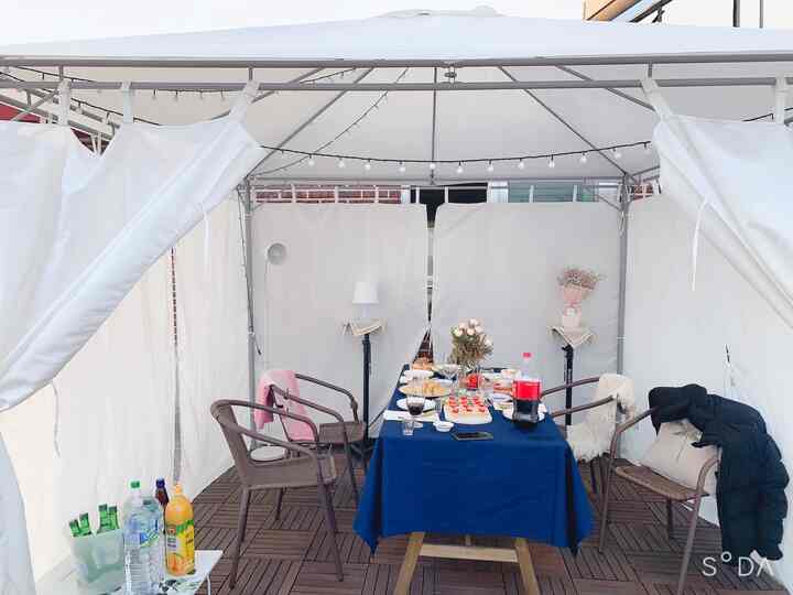 White tent featuring wood-tone outdoor table and chairs set up for a home party gathering