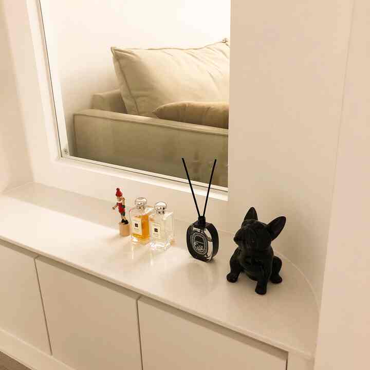 ホワイトとナチュラルトーンの玄関スペース、シューズラック上にディフューザーと小物が配置された印象的なインテリア