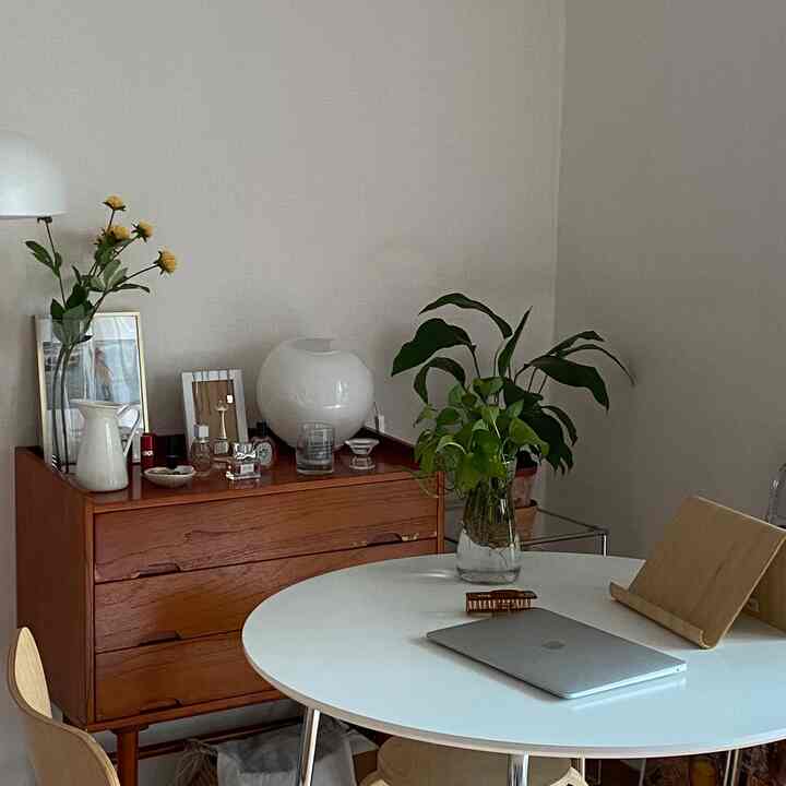 白と木目調が調和したワンルームのダイニング、丸テーブルと植物が配置されたシンプルで自然な雰囲気のインテリア